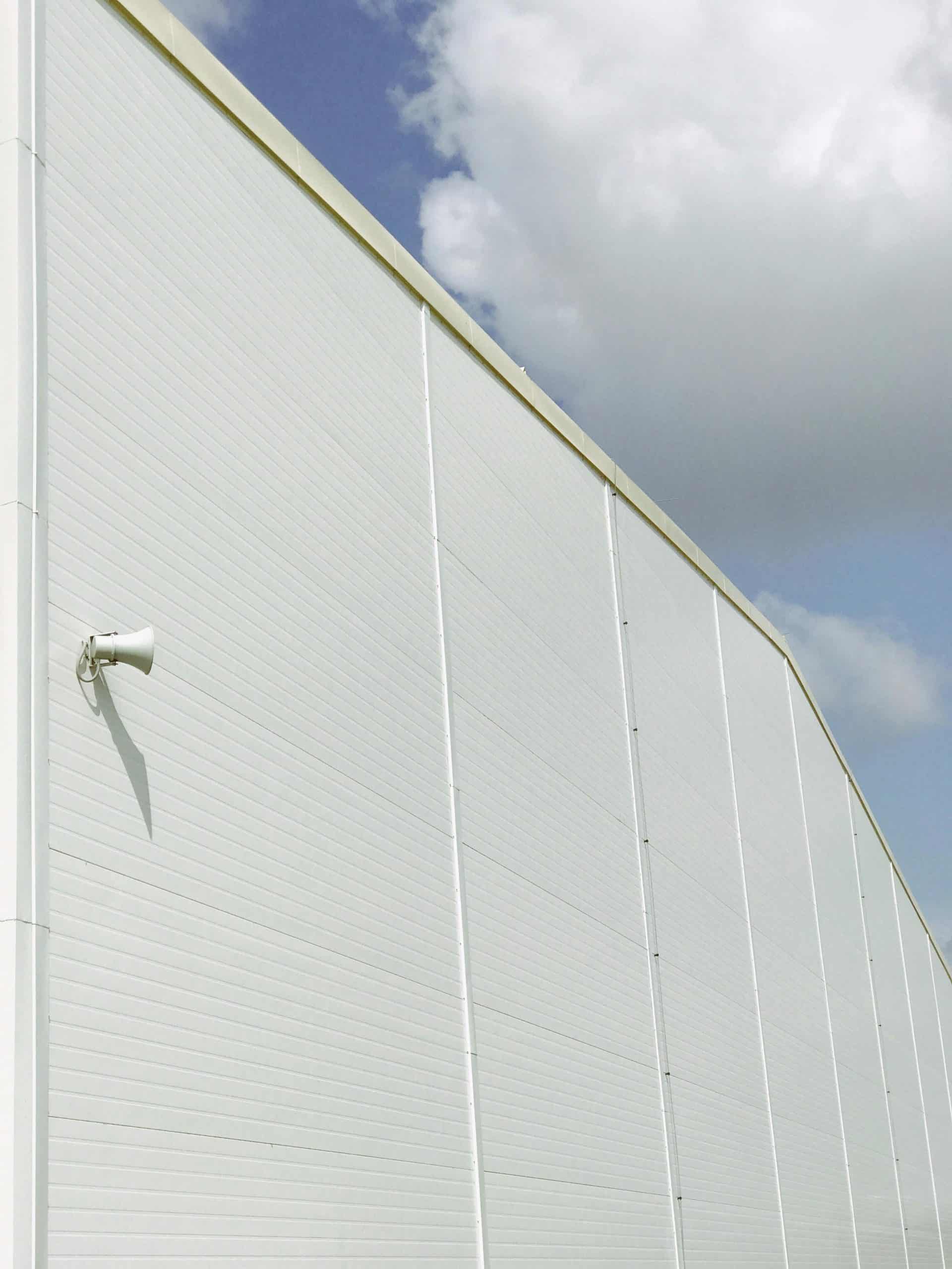 White industrial building facade against a cloudy sky in Kamianets'-Podil's'kyi, Ukraine.